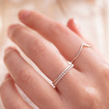 hand wearing thin plain sterling silver rings