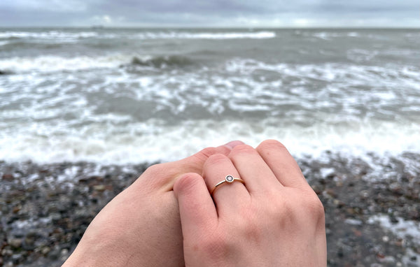 couple showing up engagement ring on beach