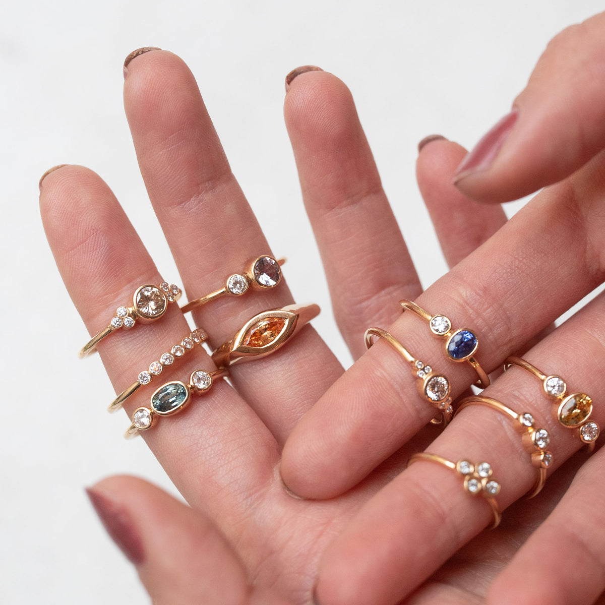 hand showing a bunch of gold rings with diamonds and sapphires
