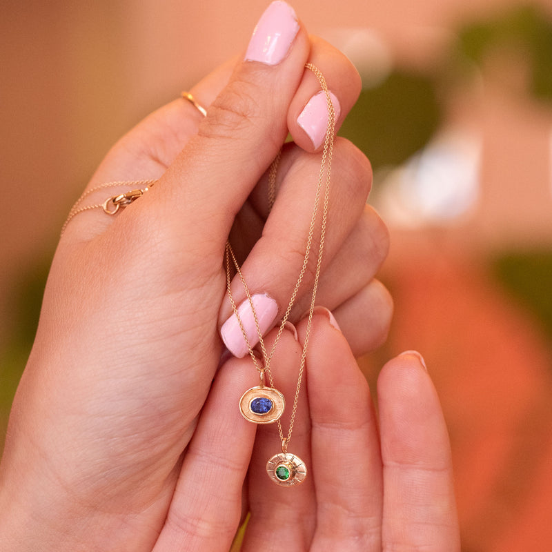talisman necklces in 18k gold, one with oval blue sapphire and one with round green garnet