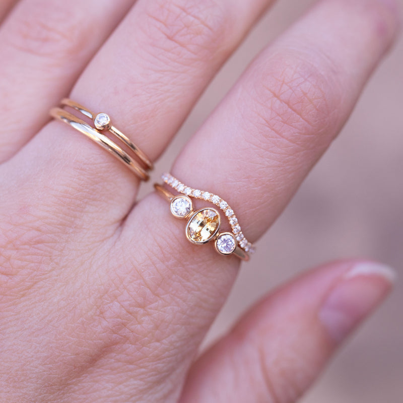 caroline hjerpe rings on hand, all in gold and with diamonds and a oval yellow sapphire